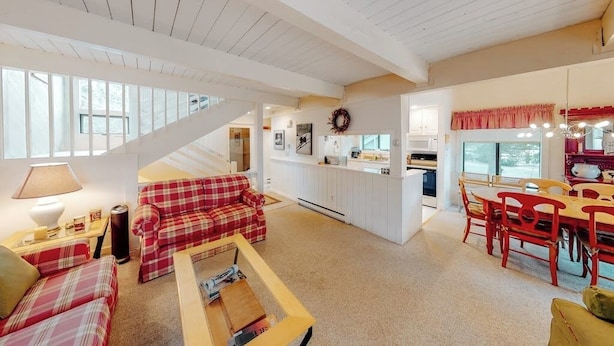 A spacious living area with a red plaid sofa, a wooden coffee table, and a dining area with red chairs.