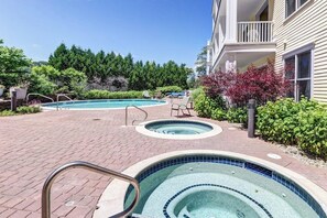 A pool area with a hot tub, lounge chairs, and a building with a balcony. - Mountain Home w/Balcony, Pool Views, Shared Pool, Hot Tub, Free WiFi, Fireplace (Stratton)