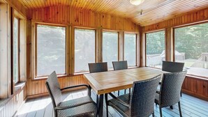 Una habitación con paneles de madera, una mesa y sillas, ventanas grandes y un ventilador de techo.