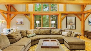 Un sofá modular grande en forma de L en una habitación con vigas de madera a la vista y un ventanal.