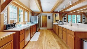 Una cocina amplia con armarios de madera, una isla central y grandes ventanales.