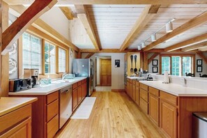 A spacious kitchen with wooden cabinets, a central island, and large windows. - Tree-lined lodge with deck, fireplaces, porch, game room, & fast WiFi (Peru)