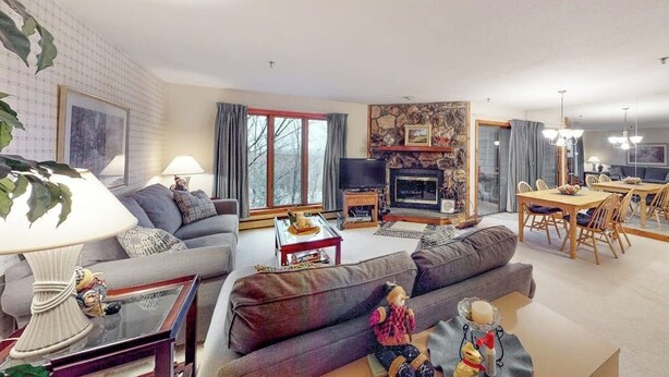 A living room with a sofa, a television, a fireplace, and a dining area with chairs and a table.