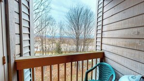 A wooden balcony with a view of trees and a distant landscape.