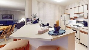 A compact kitchen with white cabinets, a microwave, a stove, and a sink.