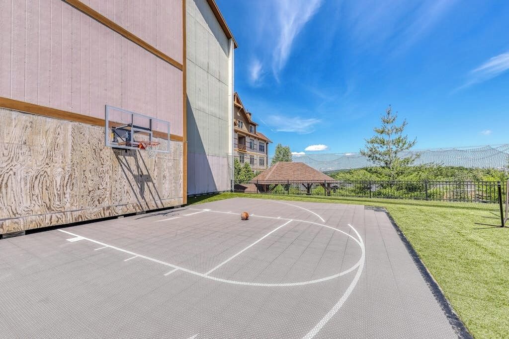 Un terrain de basket en plein air, situé à côté d’un bâtiment doté d’une grande fenêtre et d’un panier de basket.