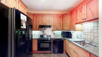 A kitchen with wooden cabinets, a black refrigerator, a stove, a microwave, and a dishwasher.