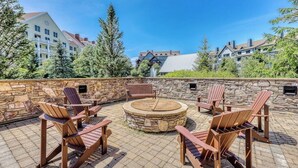 Un patio al aire libre con sillas Adirondack, un hogar de piedra y un muro de piedra.