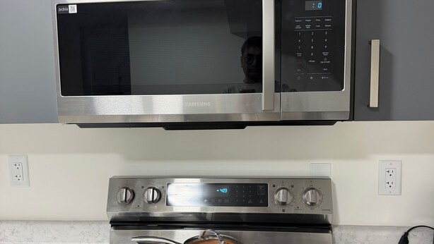 A kitchen with a stainless steel microwave and oven, a countertop with pots, and a wall-mounted oven control panel. - Brand new basement suite with private entrance, 3-5 minutes to market and parks (Saskatoon)