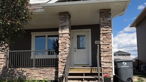 A two-story house with a stone facade, a front porch, and a visible mailbox. - Brand new basement suite with private entrance, 3-5 minutes to market and parks (Saskatoon)