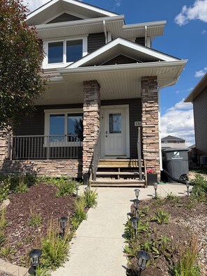 A two-story house with a stone facade, a front porch, and a visible mailbox.