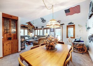 A dining area with a wooden table, chairs, and a vase of flowers. - Comfortable Townhome with Shared Pool, Private Hot Tub & Wood-Burning Fireplace (Stratton)