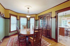 Una sala da pranzo con tavolo in legno, sedie, un lampadario e un tappeto decorato.