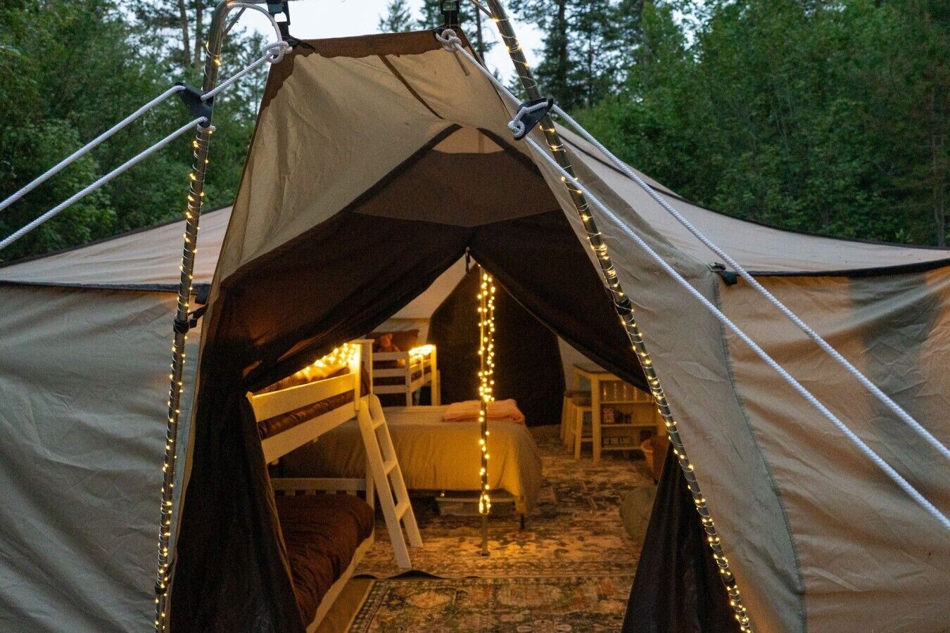 Een tent met een slaapzolder, lichtslingers en een zichtbaar bed.