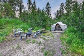 A tent with a table and chairs in a forested area.