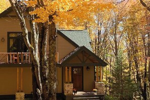 Eine zweistöckige Lodge mit Balkon, Steinpfeilern und einer Veranda mit Holzdach.