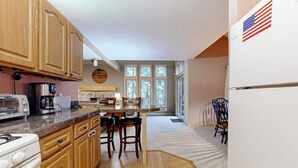 Una cucina con mobili in legno, un fornello, una macchina da caffè e una zona pranzo con sedie.