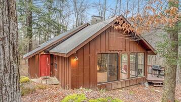 A cabin with a red door, large windows, and a deck area.