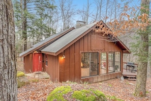 A cabin with a red door, large windows, and a deck area. - Dog-friendly cabin with forest setting, woodstove & deck - near Killington (Plymouth)