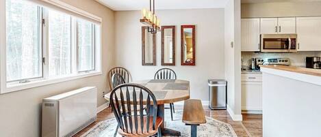 A modern kitchen with a dining area, large windows, and a central island.