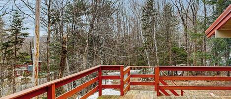 A wooden deck with red railings, surrounded by trees and a clear sky.