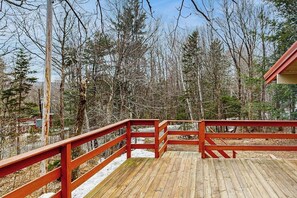 Eine Holzterrasse mit roten Geländern, umgeben von Bäumen und blauem Himmel.