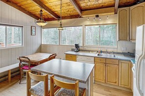 Eine Küchenzeile im Blockhausstil mit Holztisch und -stühlen, einem Einbauofen und großen Fenstern.