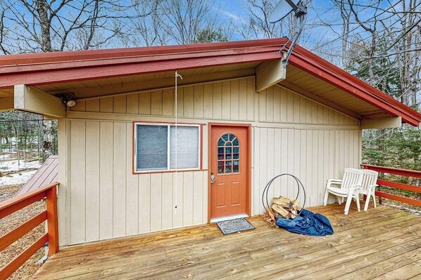 A wooden cabin with a red door, a window, and a deck with chairs. - The Last Run chalet in Snow Mountain Farms with huge deck and clubhouse pool (Wardsboro)