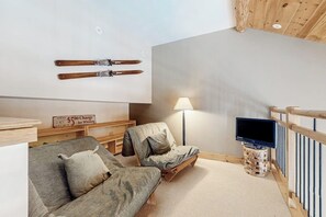 Een gezellige kamer met een bank, een stoel, een televisie en ski’s die aan de muur zijn bevestigd.
