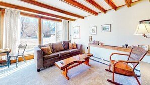 Ein gemütliches Wohnzimmer mit einer Couch, einem Holztisch, einem Schaukelstuhl und einem Esstisch.