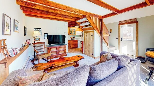 Ein Wohnzimmer mit einer Couch, einem Holztisch und einem Fernseher.