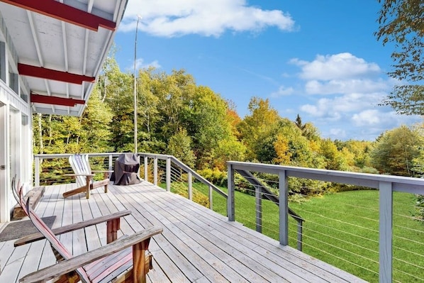 A wooden deck with a railing, a chair, and a grill. - Picturesque, Euro-style ski chalet with beautiful setting, deck & fireplace (Peru)