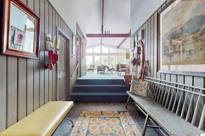 A hallway with a bench, a patterned rug, and a staircase leading to a room with a view. - Picturesque, Euro-style ski chalet with beautiful setting, deck & fireplace (Peru)