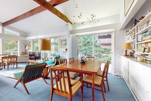 A spacious dining area with a large wooden table and chairs, a television, and a bookshelf. - Picturesque, Euro-style ski chalet with beautiful setting, deck & fireplace (Peru)