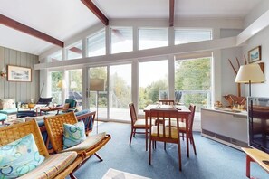 A spacious room with large windows, a dining area, and a television. - Picturesque, Euro-style ski chalet with beautiful setting, deck & fireplace (Peru)