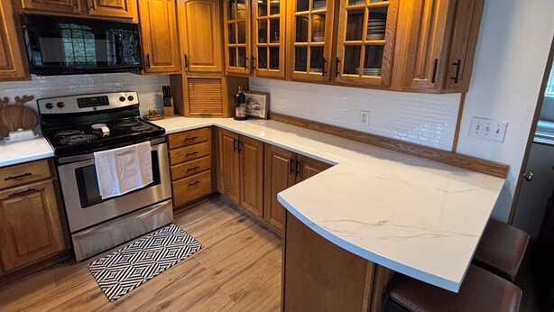 A kitchen with wooden cabinets, a stove, and a microwave. -  3-bedroom house in tranquil Millinocket (Millinocket)