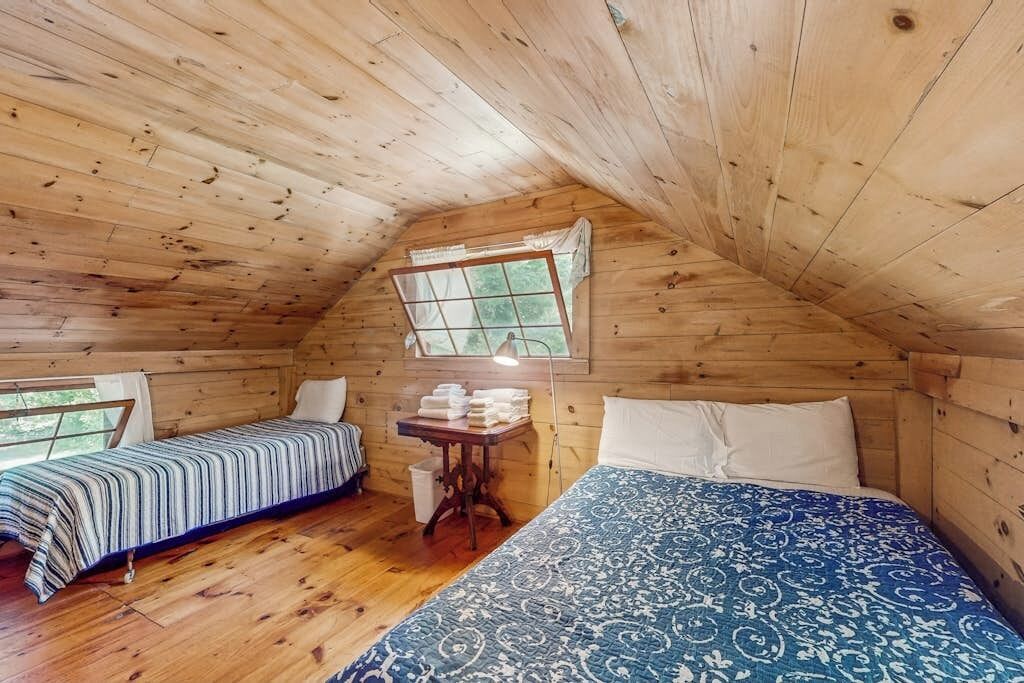 Eine Holzhütte mit zwei Betten, einem kleinen Tisch und Handtüchern sowie einem Fenster.