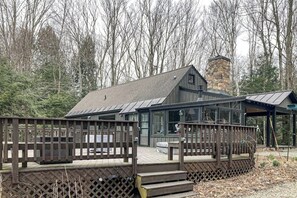 Eine Holzhütte mit einer Holzdiele, einem Steinkamin und einer Glaseinfriedung.