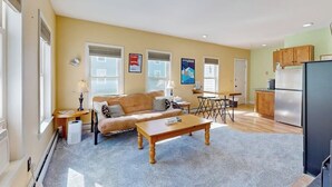 Ein Wohnzimmer mit einer Couch, einem Couchtisch und einem Essbereich mit Tisch und Stühlen.