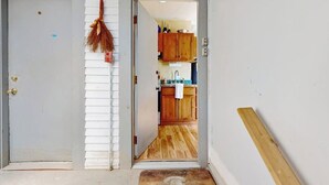 Ein Durchgang zu einer Küche mit Holzausstattung, einer Spüle und einem an der Wand hängenden Besen.
