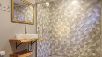 Luxe tweepersoonskamer | Badkamer | Een douche, een haardroger, handdoeken, zeep