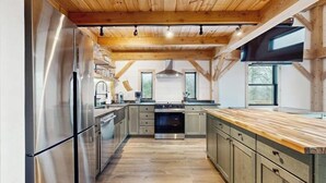 A modern kitchen with wooden beams, stainless steel appliances, and a central island.