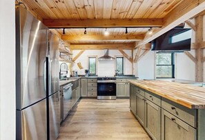 A modern kitchen with wooden beams, stainless steel appliances, and a central island.