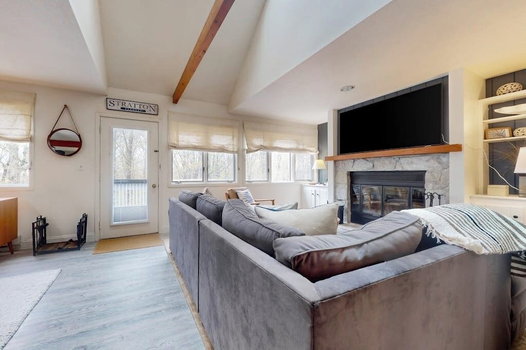 A modern living room with a sectional sofa, a fireplace, and a television.
