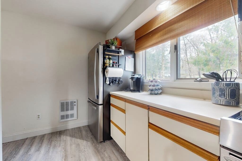 A kitchen with a built-in refrigerator, a window with a view, and a countertop with various items.