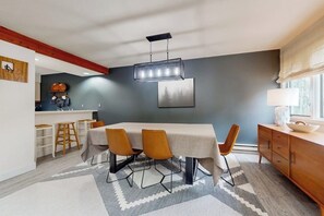 A modern dining area with a table, chairs, and a hanging light fixture. - Cozy Townhome with Shared Pool, W/D & Wood-Burning Fireplace (Stratton)
