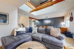 A modern living room with a sectional sofa, a wooden coffee table, and a staircase leading to an upper level.