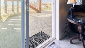 Et værelse med en skydedør, der fører til en terrasse med udsigt over stranden og bjergene.