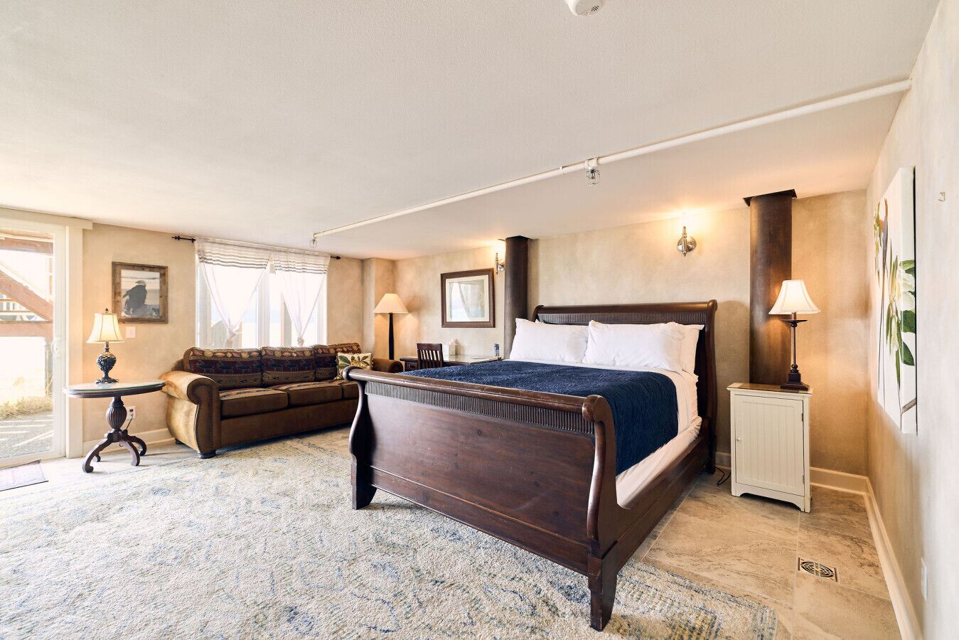 A bedroom with a large bed, a sofa, a small table, and a cabinet.