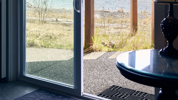 Et værelse med en skydedør, der fører ud til en balkon med udsigt over bjerge og vand.